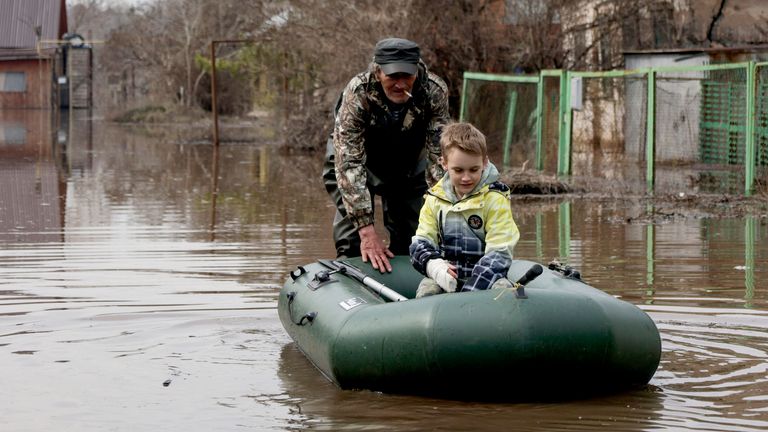 Un hombre empuja una balsa de goma con un niño en una zona inundada en Orenburg, Rusia.  Foto: AP