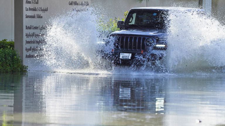 An SUV drives through floodwater covering a road in Dubai.
Pic: Reuters