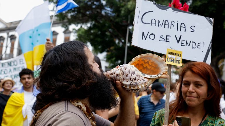 2024 年 4 月 20 日，西班牙圣克鲁斯-德特内里费，一名男子在加那利群岛旅游模式变革示范活动中以传统方式演奏海螺。图片来源：Reuters/Borja Suarez