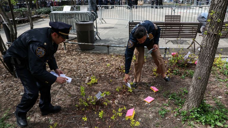 Police officers collect pamphlets dropped by a person who set themselves on fire. Pic: Reuters