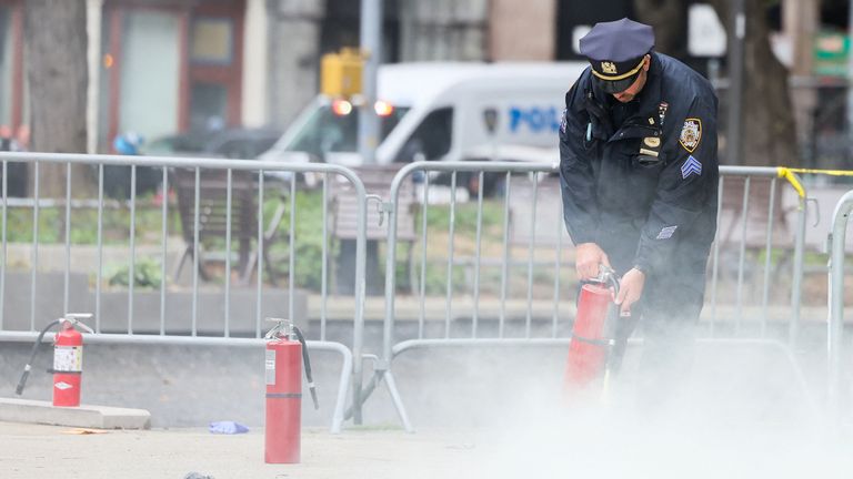 A police officer uses a fire extinguisher as emergency personnel respond to the scene where a person was covered in flames. Pic: Reuters