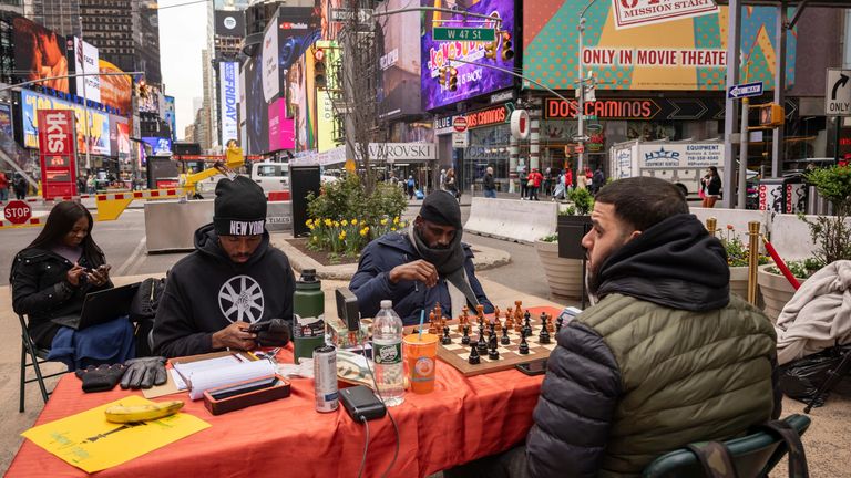 Tunde Onakoya, center,  Nigerian chess champion and child education advocate, plays a chess game in Times Square, Friday, April 19, 2024, in New York. (AP Photo/Yuki Iwamura)