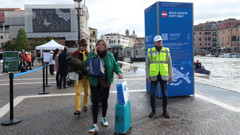A controller officer directs tourists to the information centre where they can register to pay the fee. Pic: Reuters