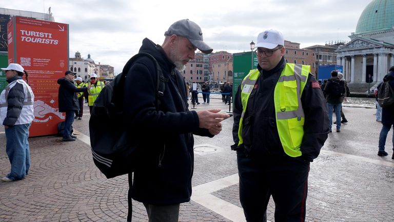 An official checks a tourist has a QR code on his smartphone to prove his payment of a fee for day. Pic: Reuters