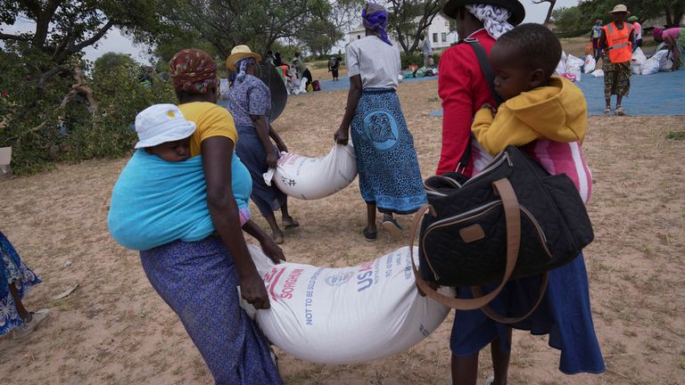 Zanyiwe Ncube, left, carries a bag of sorghum during a food distribution in Mangwe district in southwestern Zimbabwe, Friday, March, 22, 2024. A new drought has left millions facing hunger in southern Africa as they experience the effects of extreme weather that scientists say is becoming more frequent and more damaging. (AP Photo/Tsvangirayi Mukwazhi)