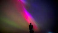 The aurora borealis, also known as the northern lights, glow on the horizon at Another Place by Anthony Gormley, Crosby Beach, Liverpool , Merseyside . Picture date: Friday May 10, 2024. PA Photo. See PA story WEATHER Aurora. Photo credit should read: Peter Byrne/PA Wire
