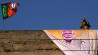 A policeman keeps watch from the roof of a building during a campaign rally by Indian Prime Minister Narendra Modi for his party. Pic: AP