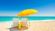 Yellow beach umbrella and deck chairs on the beach on a clear day on South beach, Miami