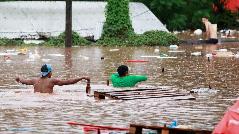 People walk in a flooded area next to the Taquari River during heavy rains in Encantado, Rio Grande do Sul state, Brazil, May 2, 2024. REUTERS/Diego Vara