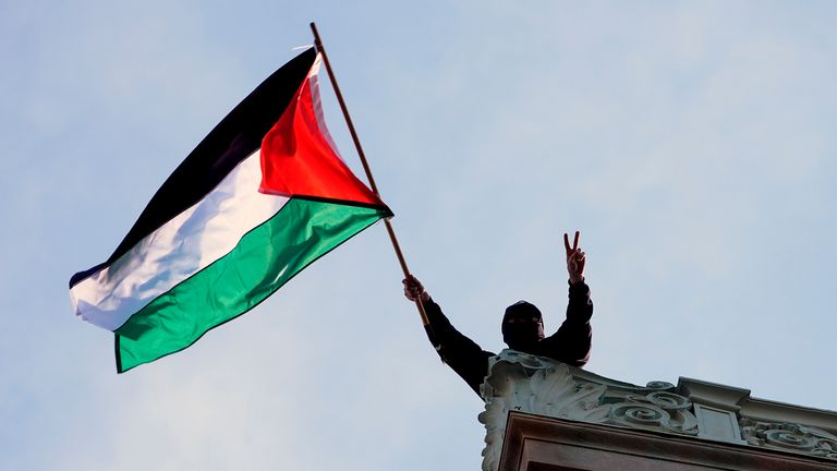 A student protester waves a Palestinian flag above Hamilton Hall on the campus of Columbia University, Tuesday, April 30, 2024, in New York. Early Tuesday, dozens of protesters took over Hamilton Hall, locking arms and carrying furniture and metal barricades to the building. Columbia responded by restricting access to campus. (Pool Photo/Mary Altaffer)