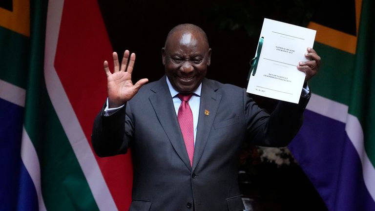 South African President Cyril Ramaphosa holds up the signed bill for a new health insurance law after this month. Pic: AP