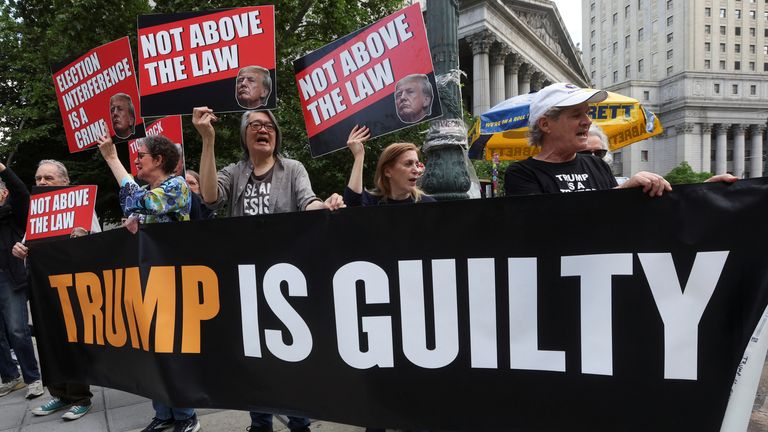 Anti-Trump demonstrators hold placards outside the court. Pic: Reuters