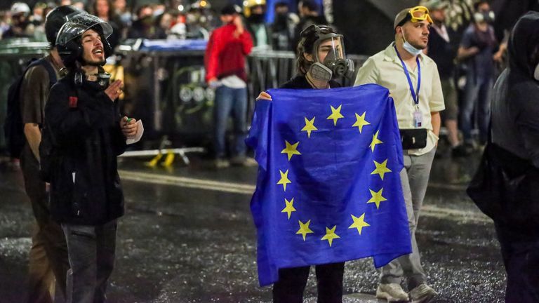 A protester holds up an EU flag in front of police. Pic: AP