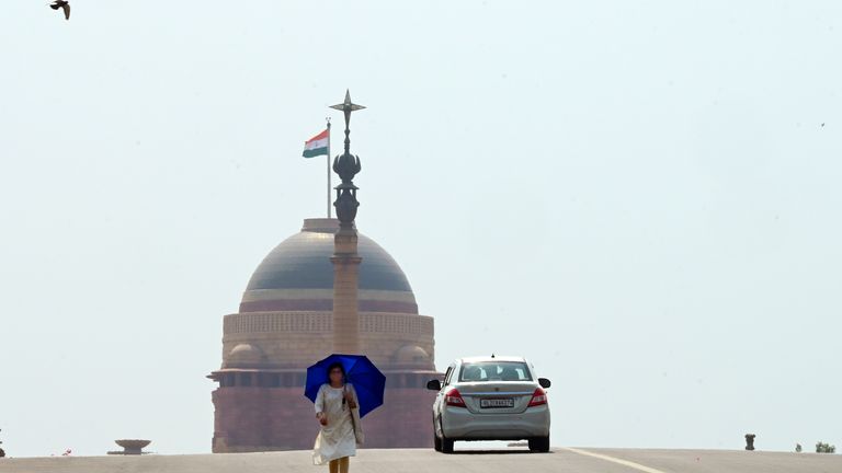 A woman walks under an umbrella as protection from severe heat in New Delhi, India on 18 May. Pic: AP