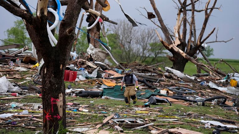 A firefighter walks among tornado-damaged homes, Tuesday, May 21, 2024, in Greenfield, Iowa. (AP Photo/Charlie Neibergall)