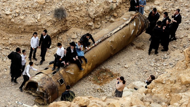 Israelis hang around apparent remains of a ballistic missile after Iran's attack in April. Pic: Reuters