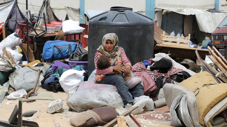 A woman sits with a child amid wreckage caused by Israeli airstrikes in Rafah. Pic: Reuters