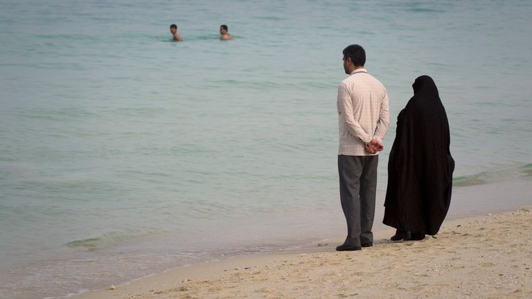 EDITORS' NOTE: Reuters and other foreign media are subject to Iranian restrictions on leaving the office to report, film or take pictures in Tehran. A couple watches swimmers as they stand on the beach of Kish Island, 1,250 kilometers (777 miles) south of Tehran April 26, 2011 . REUTERS/Caren Firouz (IRAN - Tags: SOCIETY TRAVEL)