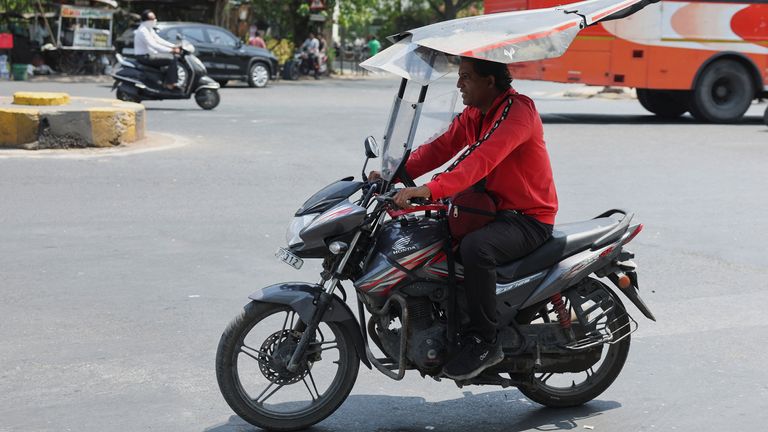 A man rides a motorcycle with a roof to protect himself from the heatwave on the street in Ahmedabad, on 25 May. Pic: Reuters