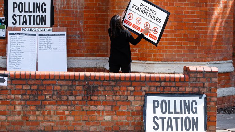 A woman attaches a sign on the wall of a polling station, during the local elections in London, Britain May 5, 2022. REUTERS/Peter Nicholls