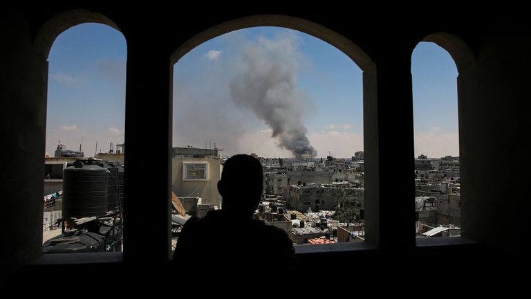 A Palestinian man watches as smoke rises after Israeli strikes in Rafah on 7 May 2024. Pic: Reuters