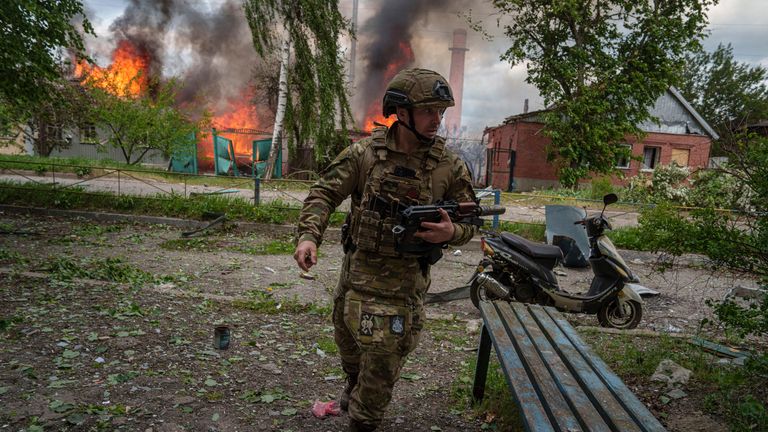 2024 年 5 月 11 日星期六，一名警察在乌克兰沃夫昌斯克被俄罗斯空袭摧毁的燃烧房屋前奔跑。（美联社照片/叶夫根尼·马洛莱特卡）