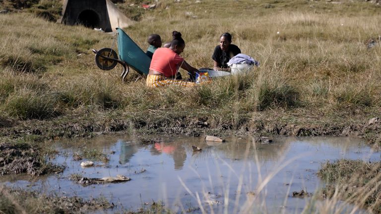 Mother of 2, Zinhle, washes clothes with dirty puddle water