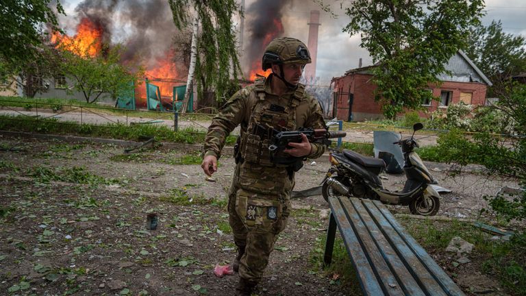 A police officer runs in front on burning house destroyed by a Russian airstrike in Vovchansk, Ukraine, on Saturday, May 11, 2024. (AP Photo/Evgeniy Maloletka)