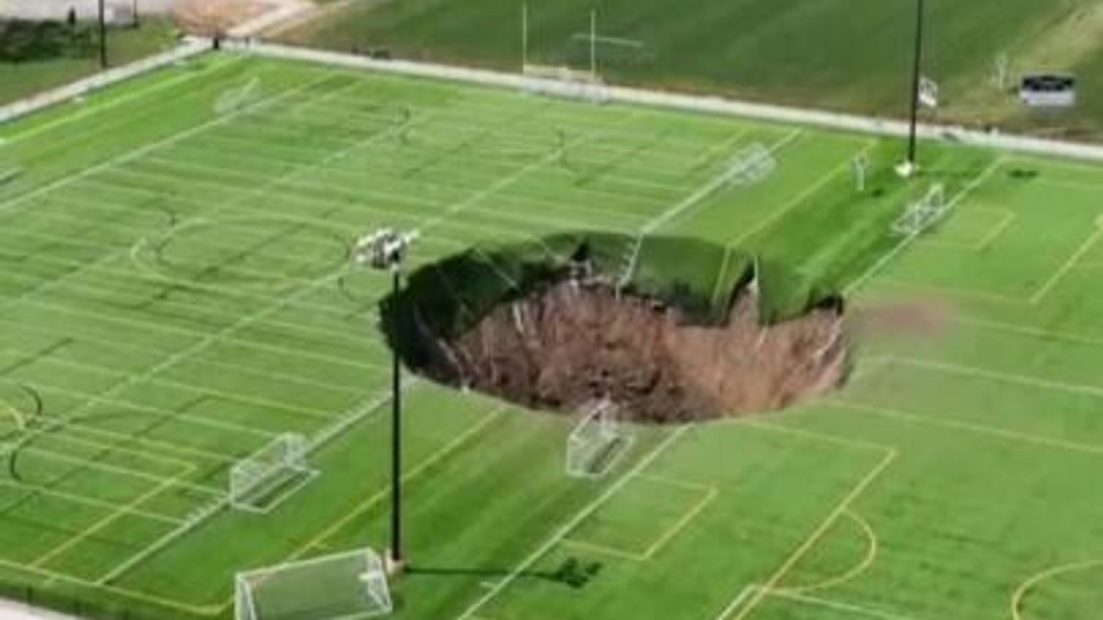 Huge sinkhole ‘100ft deep’ opens up in middle of Illinois football pitch