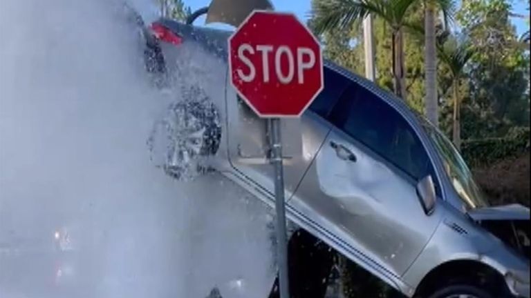 Car stuck on gushing fire hydrant 