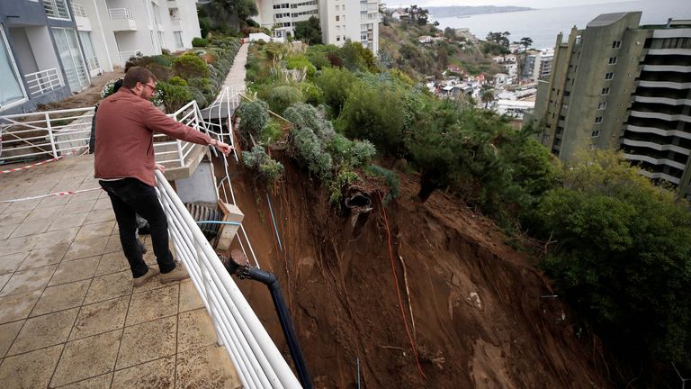 A person standing at a building complex points at a landslide after heavy rains hit Vina del Mar, Chile June 9, 2024. REUTERS/Rodrigo Garrido