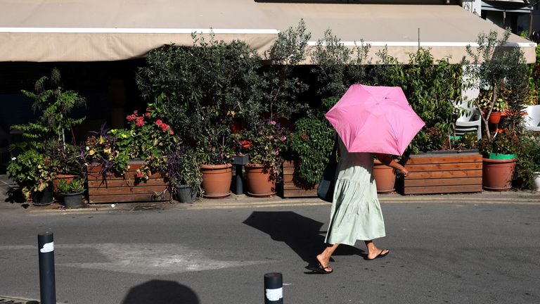 A woman shelters from the sun with an umbrella during a heatwave in Nicosia, Cyprus June 14, 2024. REUTERS/Yiannis Kourtoglou