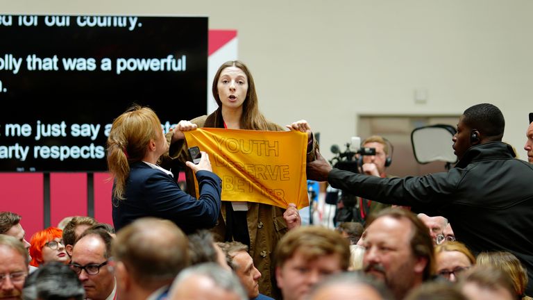 Security officers deal with a protester who held up a banner at the launch of The Labour party&#39;s 2024 general election manifesto in Manchester, England, Thursday, June 13, 2024. The election will take place on July 4. (AP Photo/Jon Super)