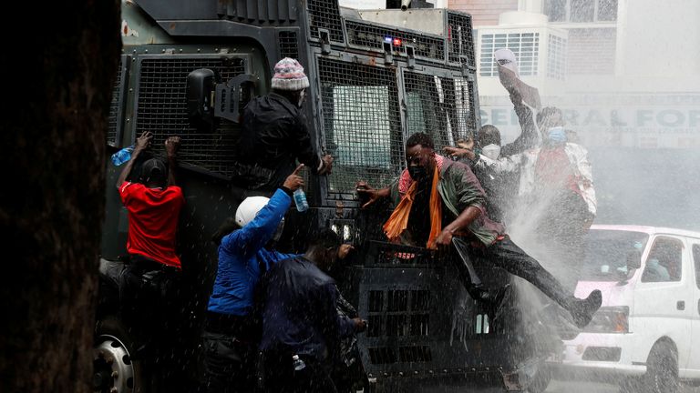 Demonstrators climb on a water cannon truck. Pic: Reuters