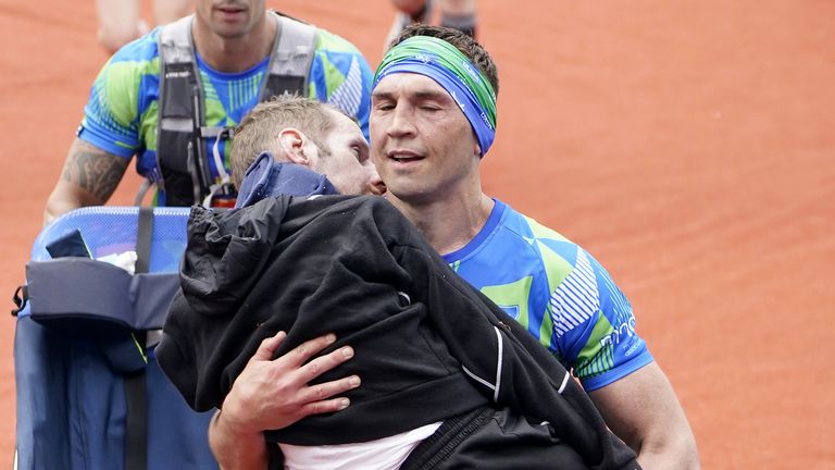 Kevin Sinfield carries Burrow over a marathon finish line in May last year. Pic: PA