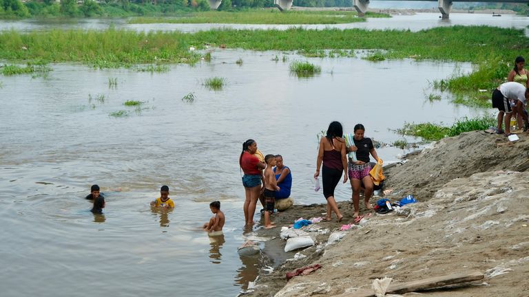Migrants bathe in the river