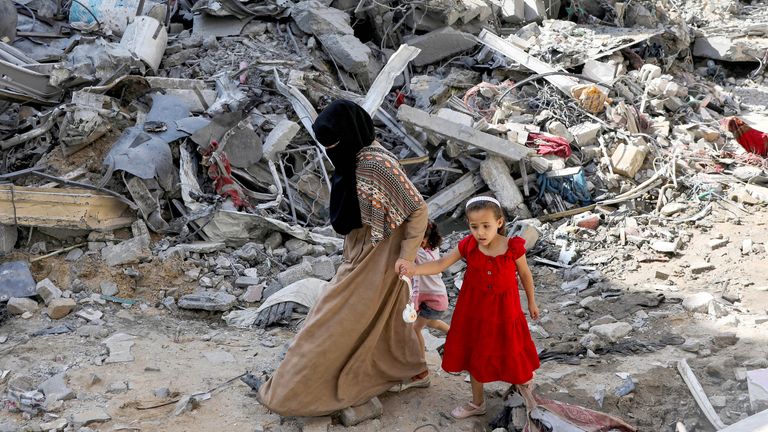 A woman and child walk among debris, aftermath of Israeli strikes at the area, where Israeli hostages were rescued 