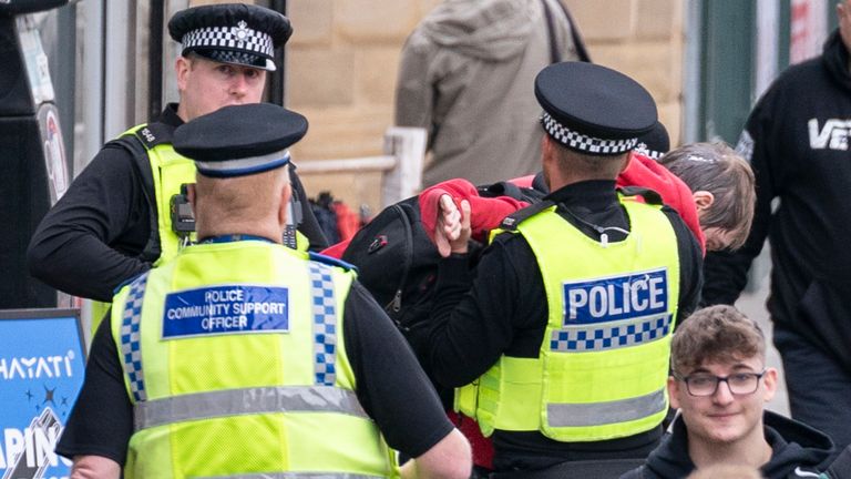 Police officers escort a person after he threw a cup towards Reform UK leader Nigel Farage on the Reform UK campaign bus in Barnsley, South Yorkshire, whilst on the General Election campaign trail. Picture date: Tuesday June 11, 2024.
