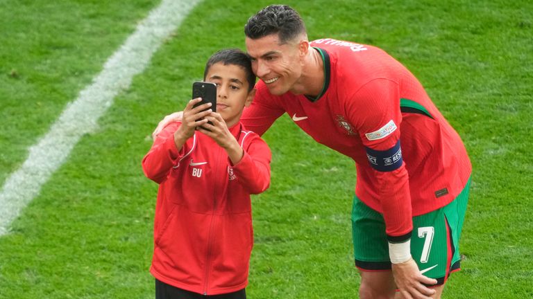 A young pitch invader takes a selfie with Portugal's Cristiano Ronaldo during a Group F match between Turkey and Portugal at the Euro 2024 soccer tournament in Dortmund, Germany, Saturday, June 22, 2024. (AP Photo/Michael Probst)