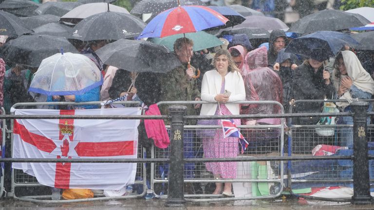 Royal fans wait in heavy rain on The Mall for the return of the royal procession to Buckingham Palace.
Pic: PA