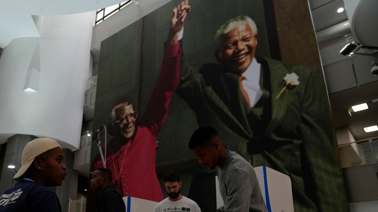 A man casts his vote beneath an image of former president Nelson Mandela and the former Anglican Archbishop Desmond Tutu at a polling station in Cape Town