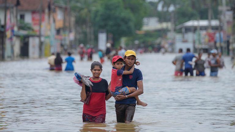 People wade through a flooded street in Biyagama, a suburb of Colombo, Sri Lanka, Monday, Jun. 3, 2023. Sri Lanka closed schools on Monday as heavy rains triggered floods and mudslides in many parts of the island nation, killing at least 10 people while six others have gone missing, officials said. (AP Photo/Eranga Jayawardena)
