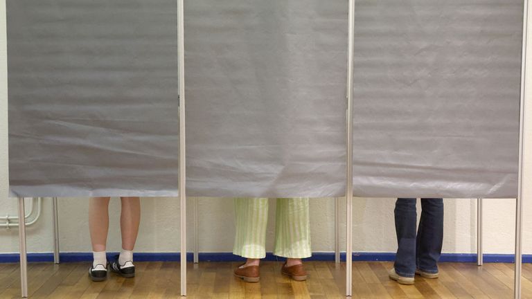 People stand in voting booths in Tulle.
Pic: Reuters