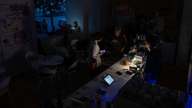A worker speaks to customers in a coffee shop during power cuts in Kyiv, Ukraine, Friday, June 7, 2024. (AP Photo/Alex Babenko)