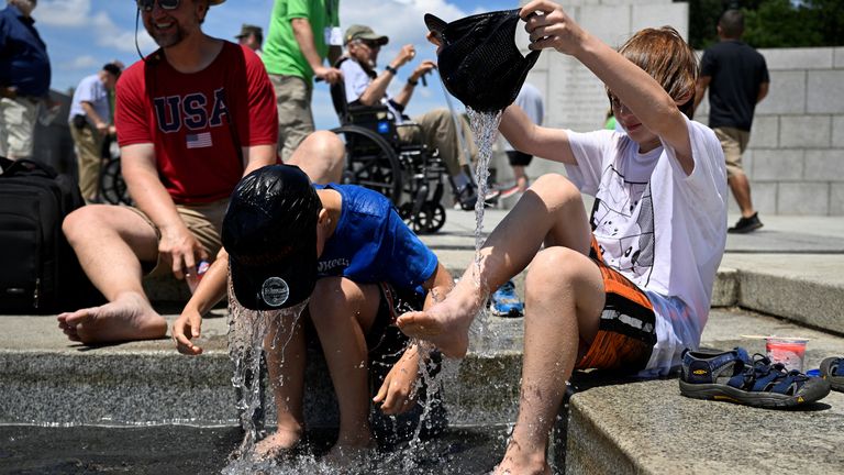 Noah Laginess, 11, and his brother Nicholas Laginess, 8, cool off in the fountain of the World War II Memorial as their father Michael Laginess looks on, amid a heat wave in Washington, U.S., June 19, 2024. REUTERS/Craig Hudson
