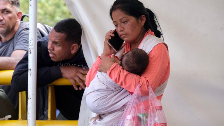 A woman and baby wait near the checkpoint