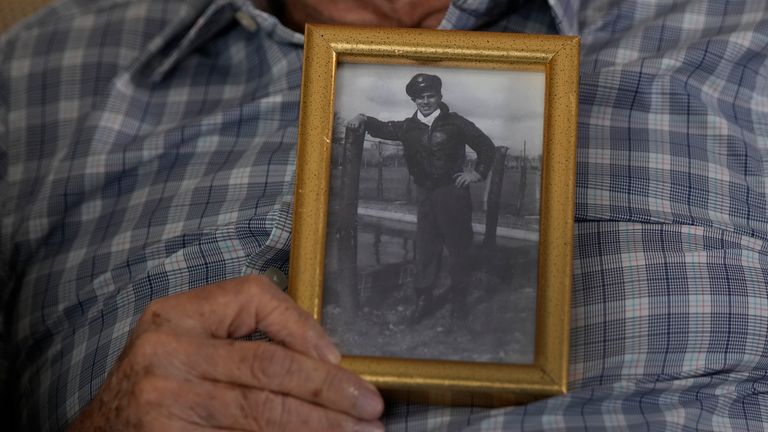 World War II veteran Harold Terens, 100, holds a photo of himself during the war when he was 20-years-old, Thursday, Feb. 29, 2024, in Boca Raton, Fla. Terens will be honored by France as part of the country's 80th anniversary celebration of D-Day. In addition, he will marry Jeanne Swerlin, 96, on June 8 at a chapel near the beaches where U.S. forces landed. (AP Photo/Wilfredo Lee).