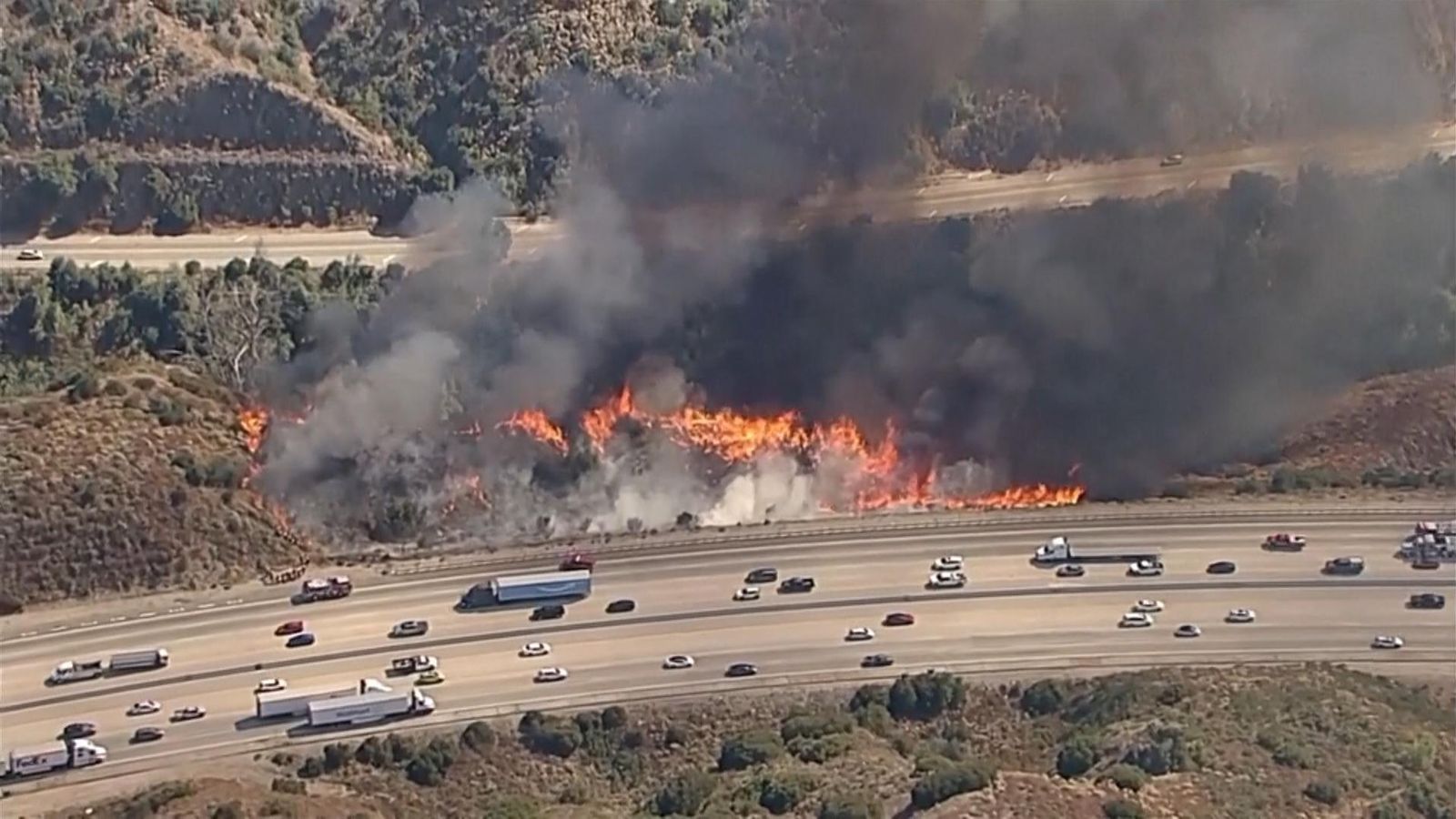 Cars pass by brush fire burning in Los Angeles National Forest | US ...