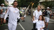 Press agency photographer Christina Assi, right, holds the Olympic torch with. Nicolas Payeur, left, at the 2024 Summer Olympics, Sunday, July 21, 2024, in Vincennes, outside Paris, France. Assi was struck by a tank shell on Oct. 13, 2023 while reporting clashes between the Israeli army and armed groups in southern Lebanon. (AP Photo/Thomas Padilla)