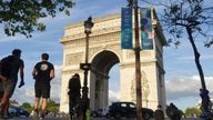 People sit on a bench in front of the Arc de Triomphe beside an advertising flag for the Paris 2024 Olympic and Paralympic Games in Paris, France, July 6, 2024. REUTERS/Fabrizio Bensch